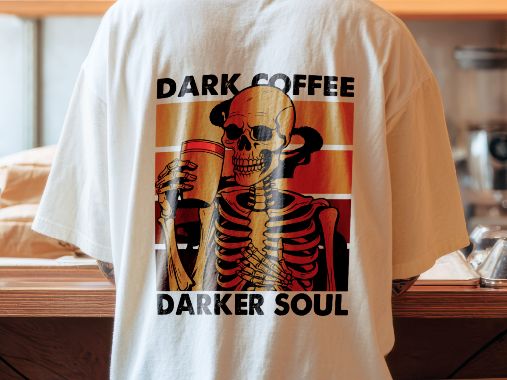 06 Food and drink humor Back of a white t-shirt showing a skeleton holding a coffee cup, with the text "Dark Coffee, Darker Soul" in bold black letters.