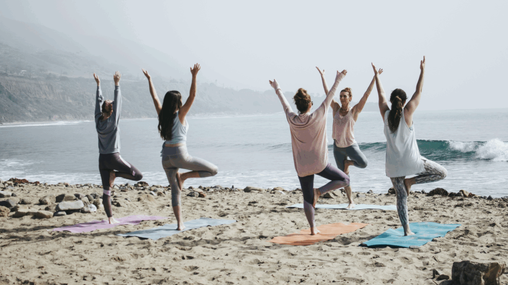 A person practicing yoga on a sandy beach with waves gently crashing in the background under a clear blue sky What is a Niche? 5 Examples of Print on Demand niche ideas 5