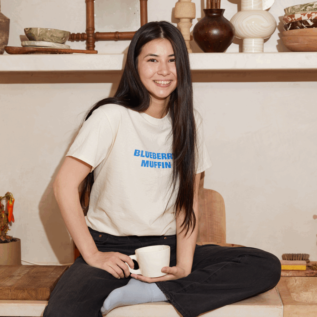 Choose Printify for printing images on shirts A smiling young woman wearing a light “Blueberry muffin” t-shirt.