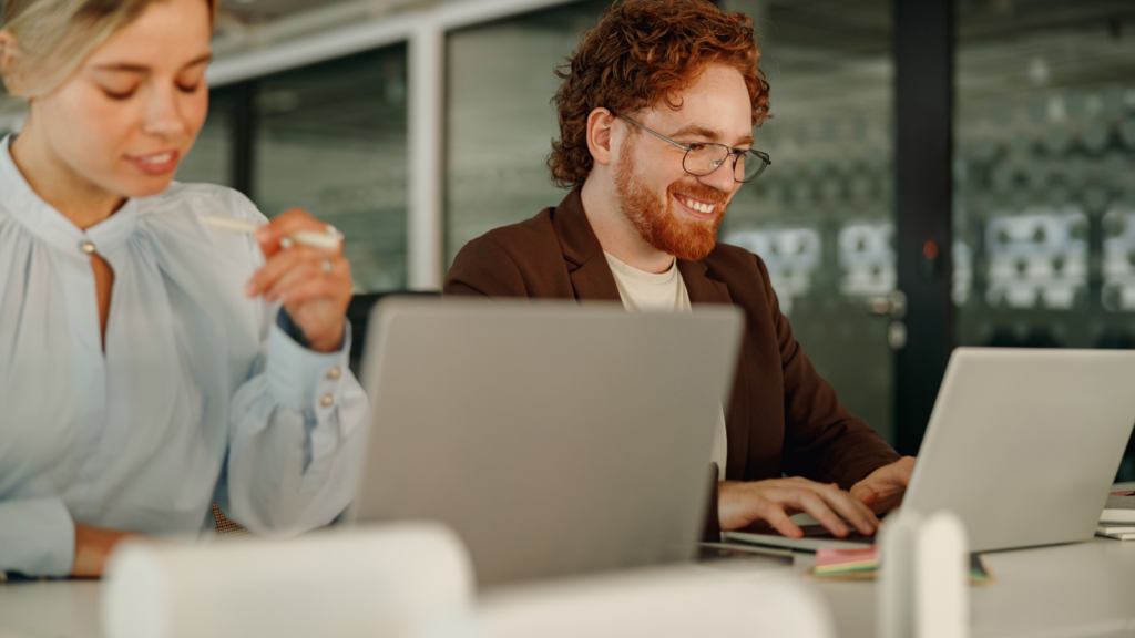 Develop a business plan A man and woman sit together at a table, both working on laptops, immersed in their tasks.