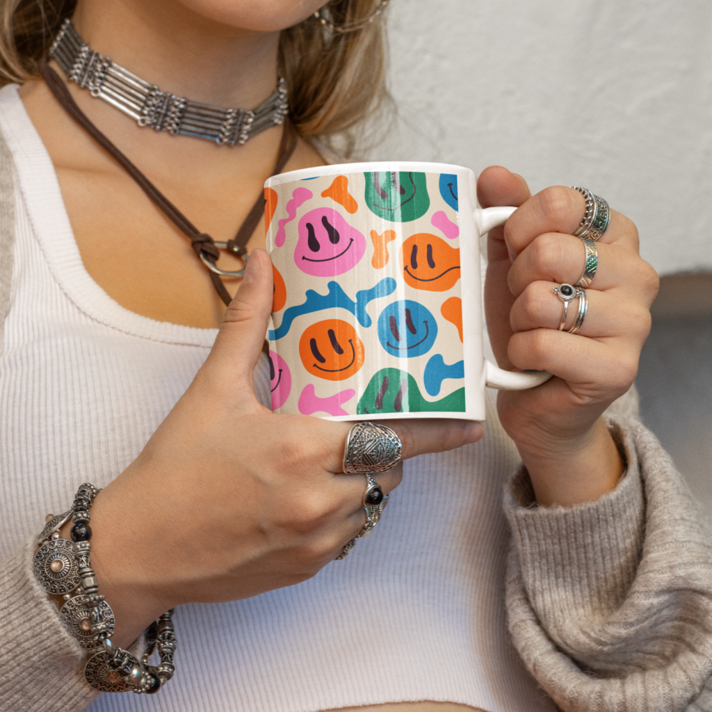 Mugs and water bottles A woman holding a mug with a custom illustrated smiling faces print.
