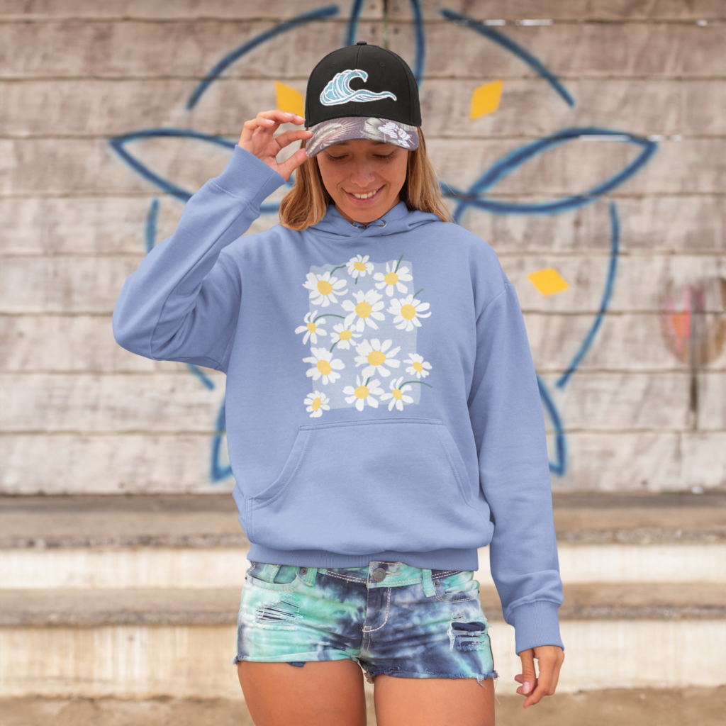 Nature inspired illustrations A woman in a trending blue hoodie with a floral print and denim shorts standing in front of a wall.
