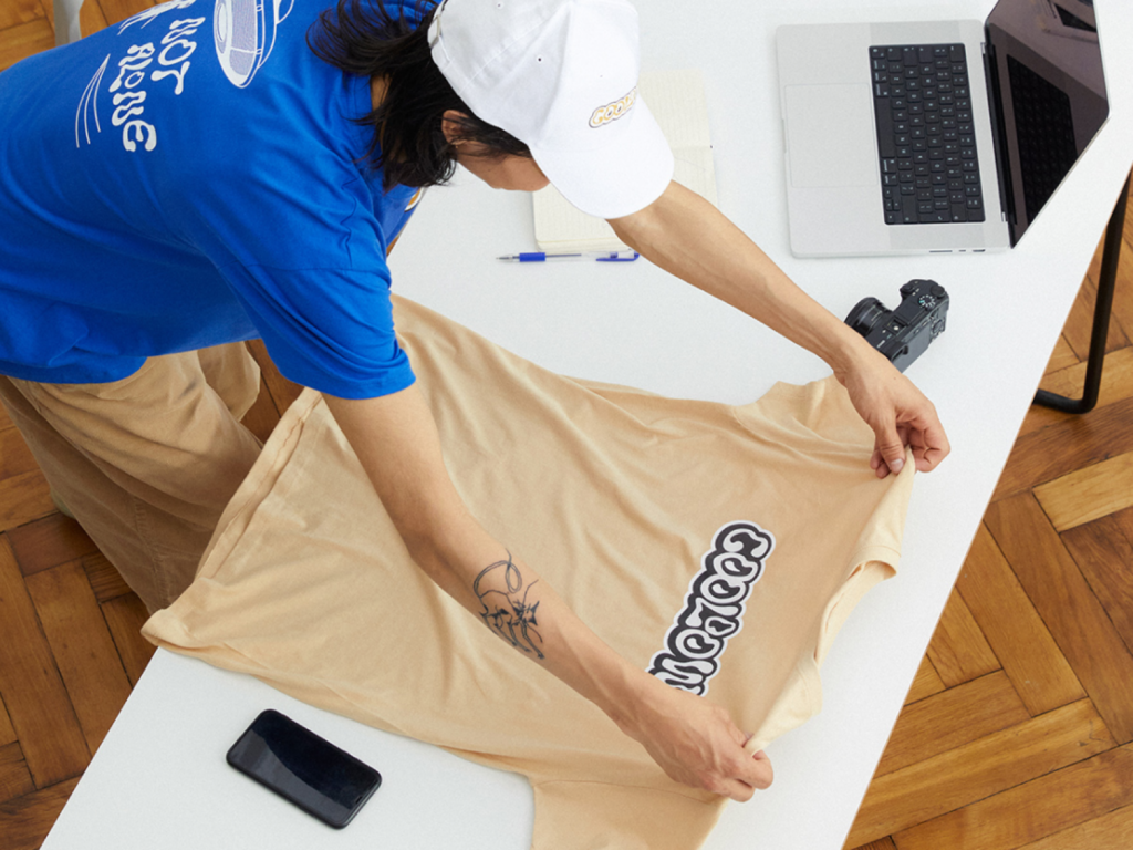 Start affiliate marketing through Pinterest with Printify A person checking out a custom beige t-shirt made with print-on-demand.
