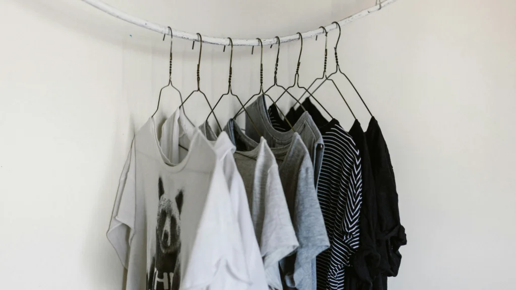 T shirt design placement options and sizes A white wall displaying various clothes neatly hung on hangers.