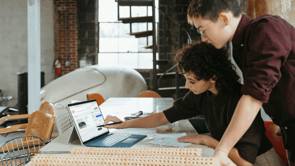 Two colleagues collaborating on a laptop in a modern office setting What is a Niche? 5 Examples of Print on Demand niche ideas 7